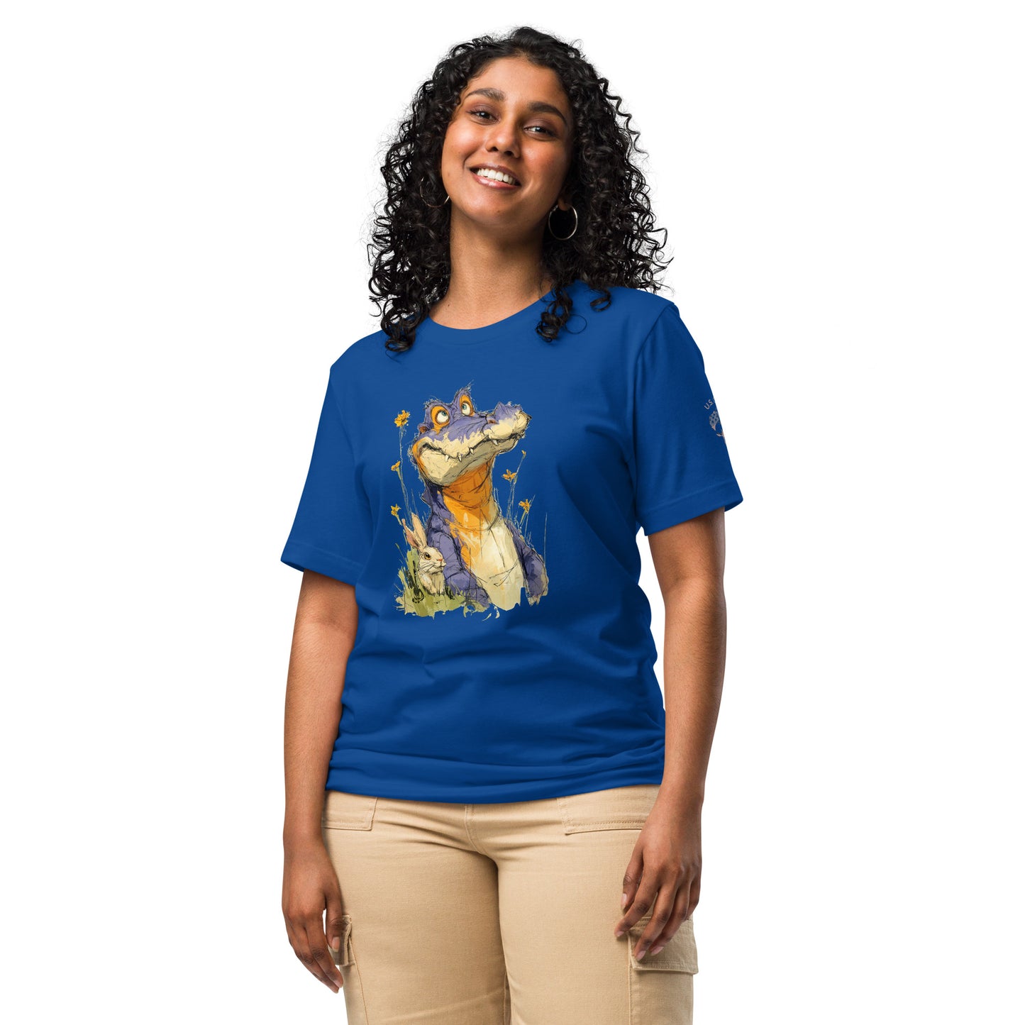 Product mockup. A woman in beige pants wearing a royal blue T-shirt with a big cartoon alligator and little rabbit surrounded by tall yellow wildflowers on the front.