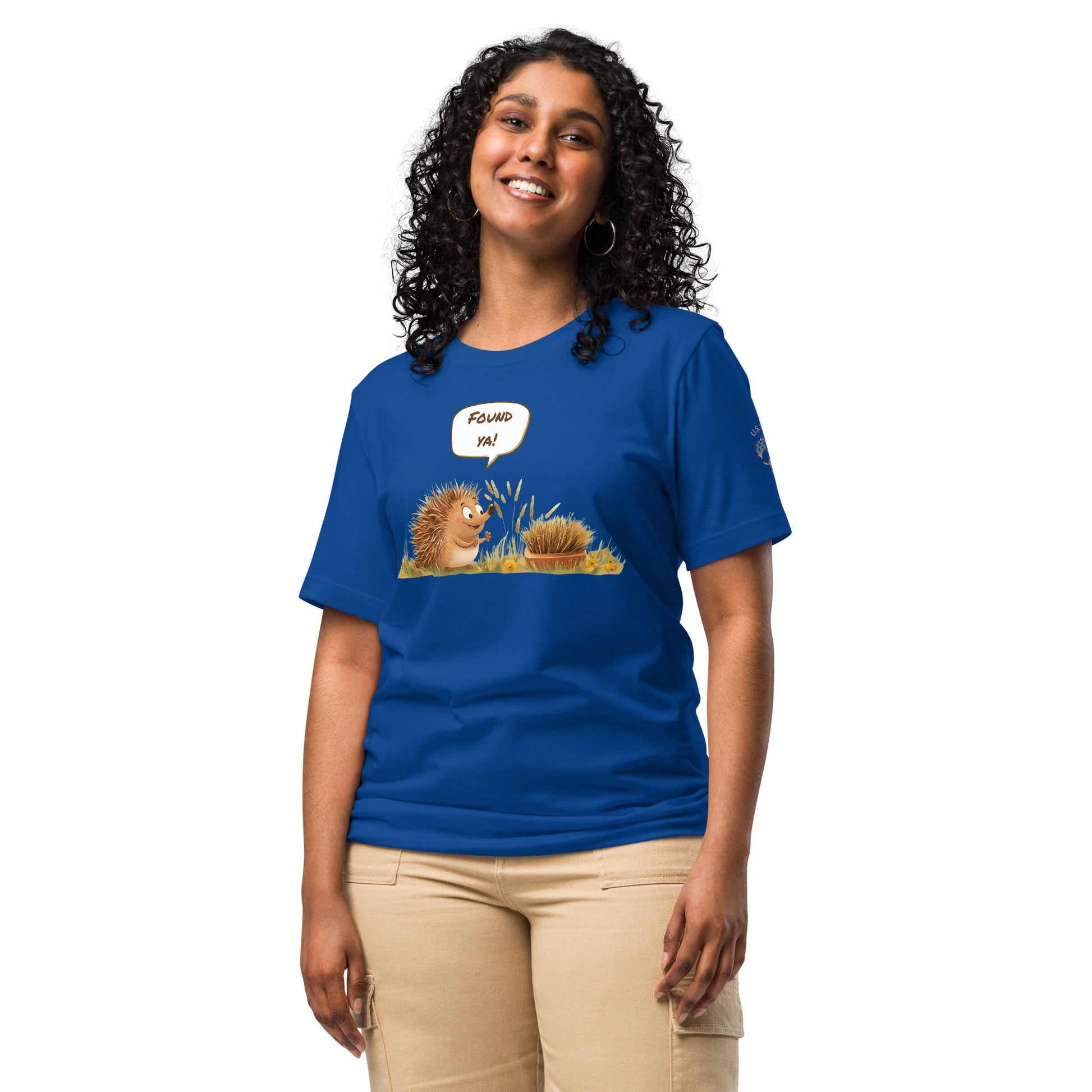 Product mockup. Woman in beige pants wearing a blue T-shirt with two illustrated hedgehogs, one exclaiming in a speech bubble “Found ya!”