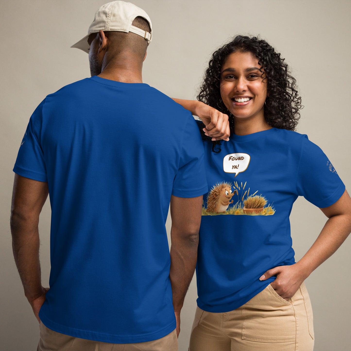 Product mockup. Man in tan cargo pants and boots in a blue T-shirt decorated with two animated hedgehogs, one popping out and yelling “Found ya!”