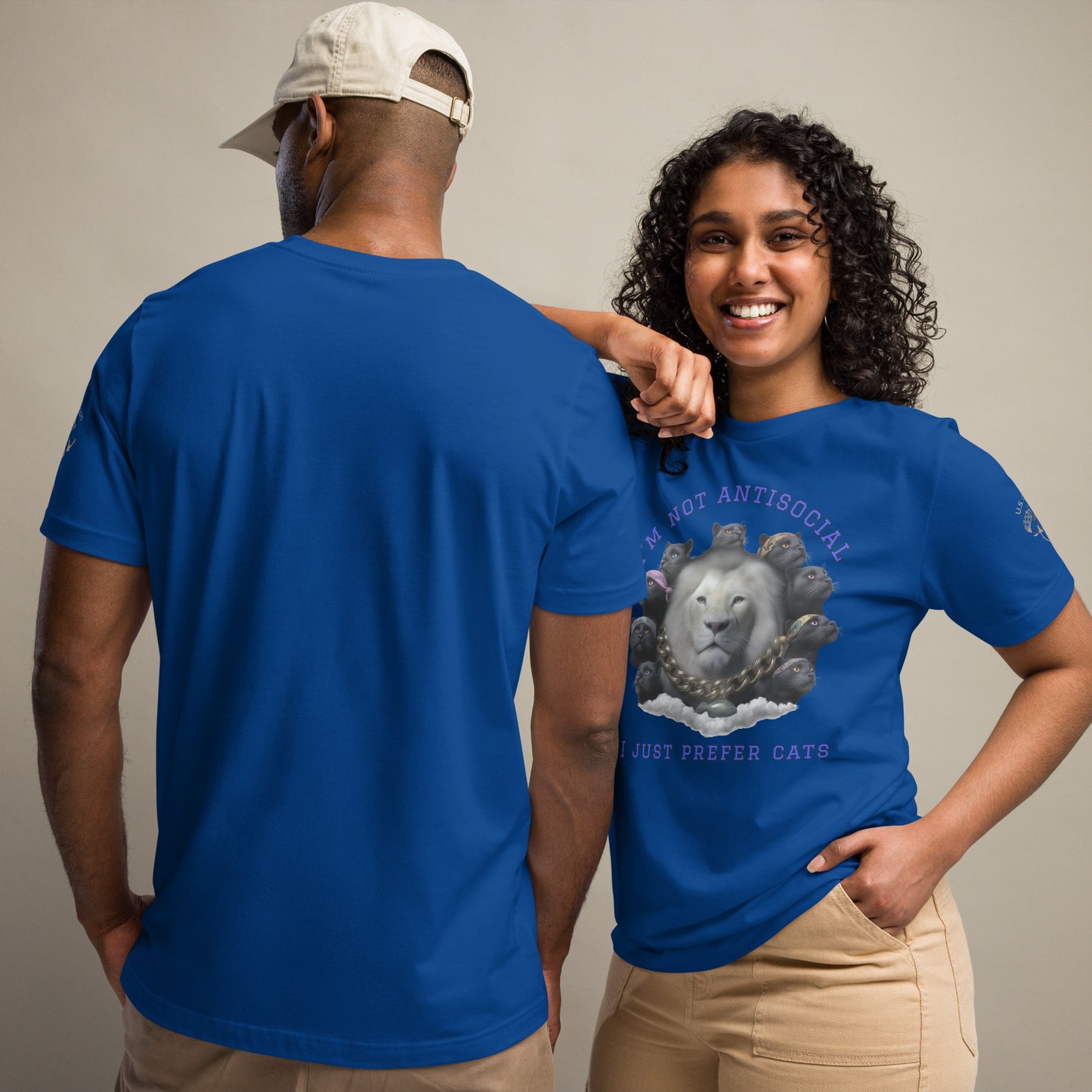 Product mockup. Man and woman in beige pants, with the woman wearing a blue T-shirt showing a gray lion’s head ringed by cats, text above says “I’m Not Antisocial I Just Prefer Cats.”