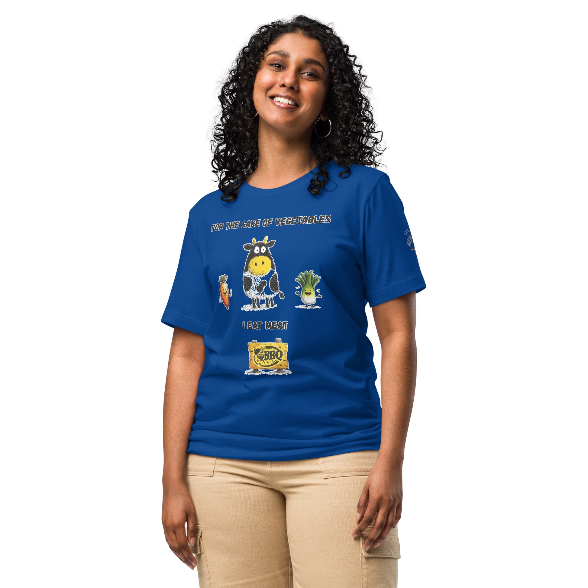 Product mockup. Woman in beige pants modeling a blue T-shirt with a cartoon cow, carrot, leek, and “For the sake of vegetables I eat meat” and a yellow BBQ sign.