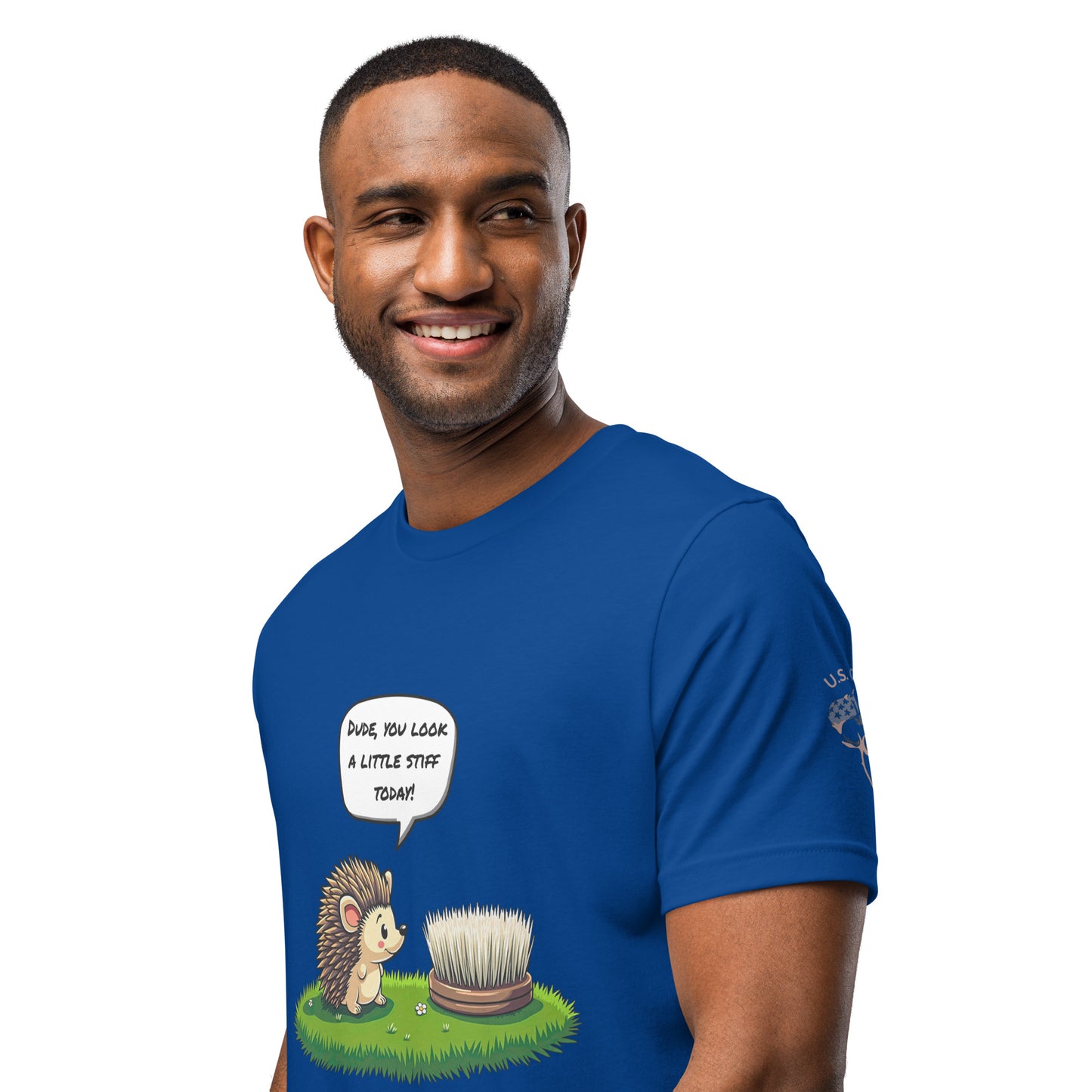 Product mockup. Blue T-shirt, left front, cartoon hedgehog says “Dude, you look a little stiff today!” to a dish brush on grass.