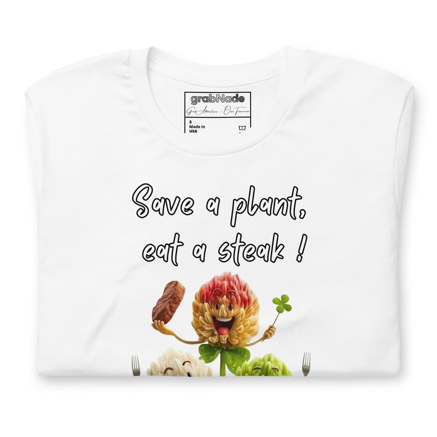 Product mockup. Folded white T-shirt with cartoon flowers, forks, steak, and text: “Save a plant, eat a steak!”
