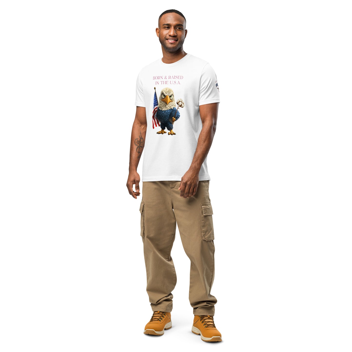 Product mockup. Person standing wearing white T-shirt displaying stylized eagle holding American flag and cotton stem with 'Born & Raised in the U.S.A.' text, khaki cargo pants, and tan boots.