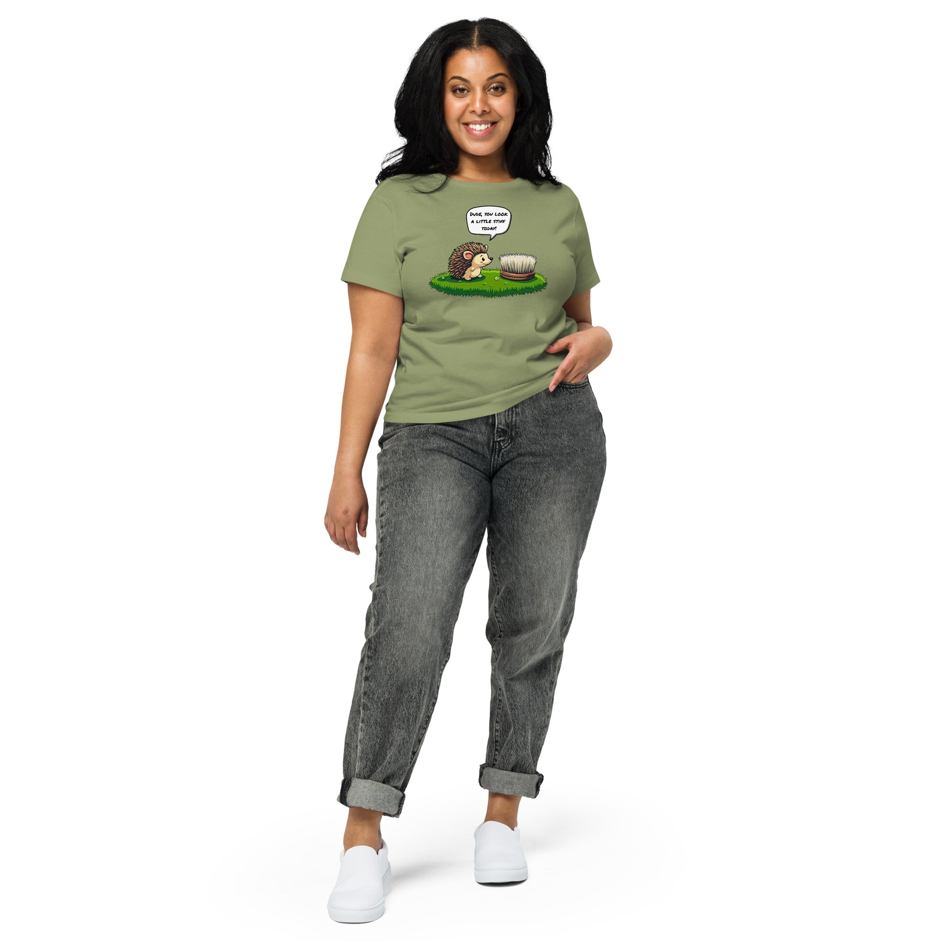 Product mockup. Full-body view of a woman standing and wearing a light green high-waisted t-shirt with the hedgehog and scrubbing brush cartoon graphic on the front. She is also wearing relaxed-fit gray jeans and white shoes. The setting is a plain white background.