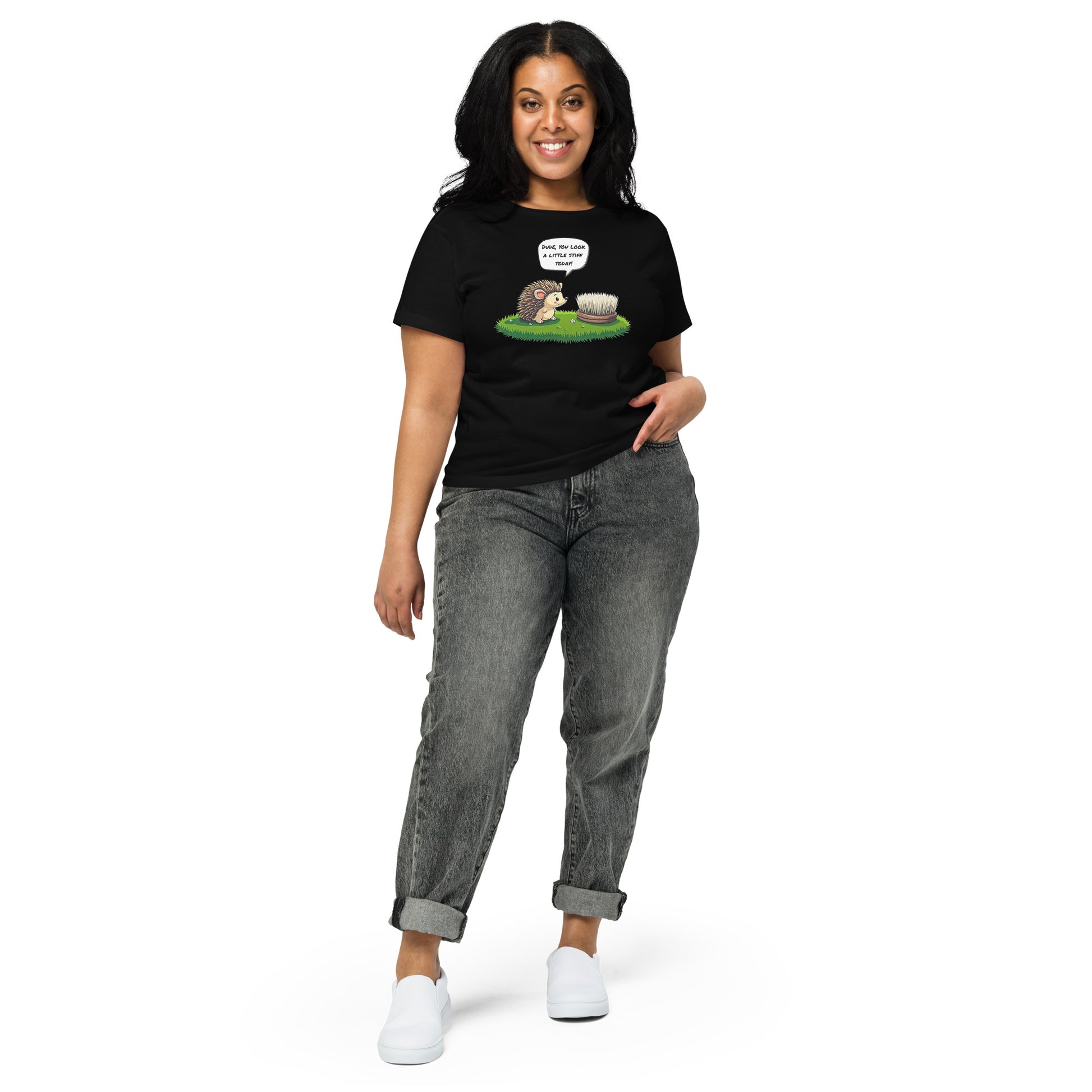 Product mockup. Full-body view of a woman standing and wearing a black high-waisted t-shirt with the hedgehog and scrubbing brush cartoon graphic on the front. She is also wearing relaxed-fit gray jeans and white shoes. The setting is a plain white background.