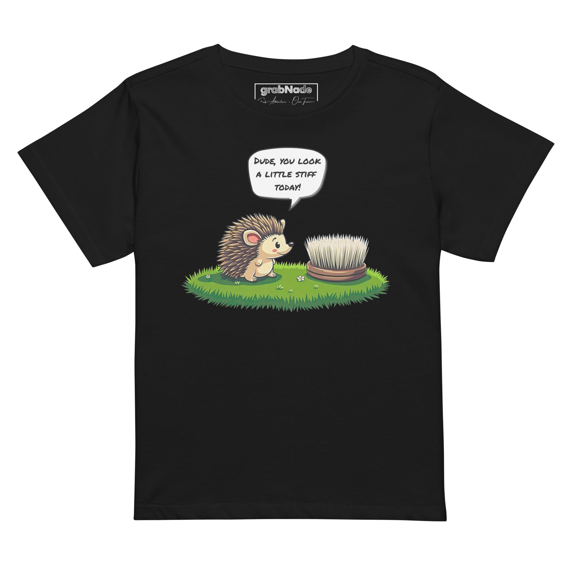 Product mockup. Black high-waisted women's t-shirt laid flat against a plain background. A colorful cartoon graphic of a hedgehog with a speech bubble—'Dude, you look a little stiff today!'—faces a scrubbing brush on grass. The shirt label at the collar reads 'grabNade.