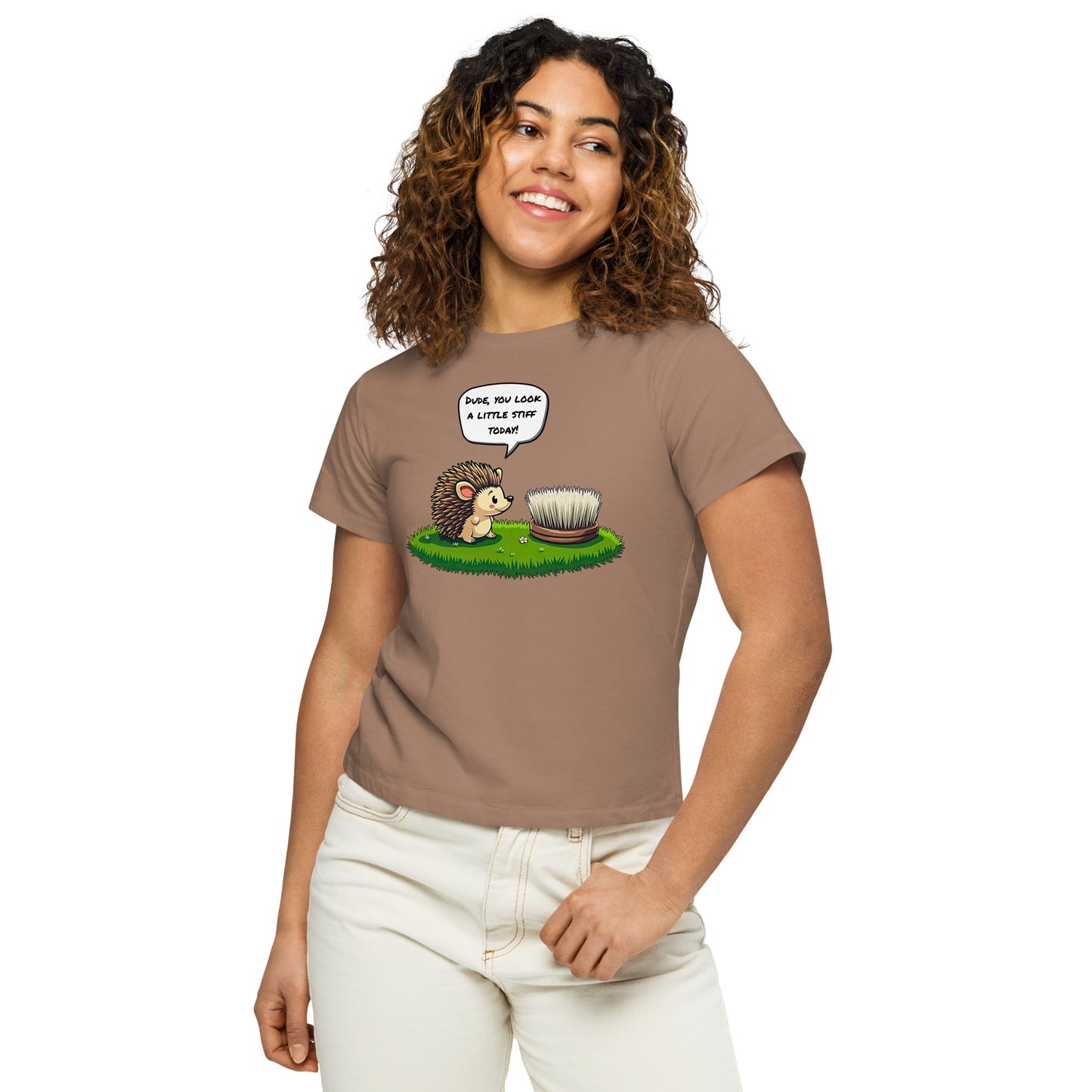 Product mockup. Close-up, front view of a woman in a latte high-waisted t-shirt with a playful hedgehog and scrubbing brush design. She has curly hair, is smiling, and wears light-colored jeans, posing against a white background.