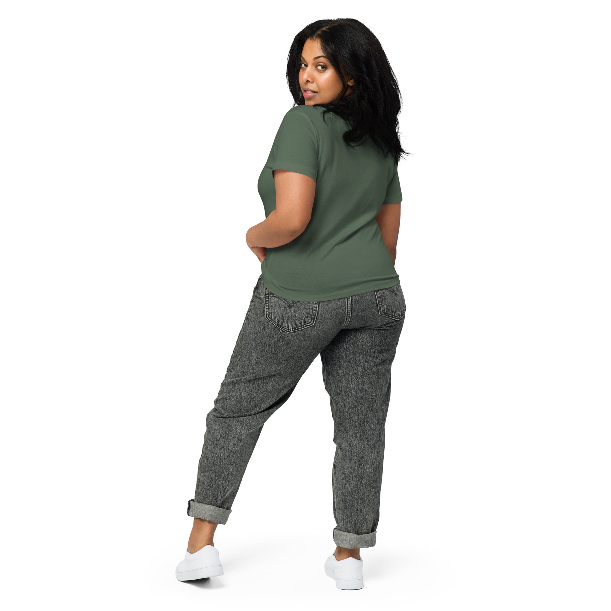 Product mockup. Back view of a woman wearing a green pine high-waisted t-shirt and light-colored pants. The back of the shirt is plain with no graphics or text, and she is turning her head to look at the camera, set against a clean white backdrop.