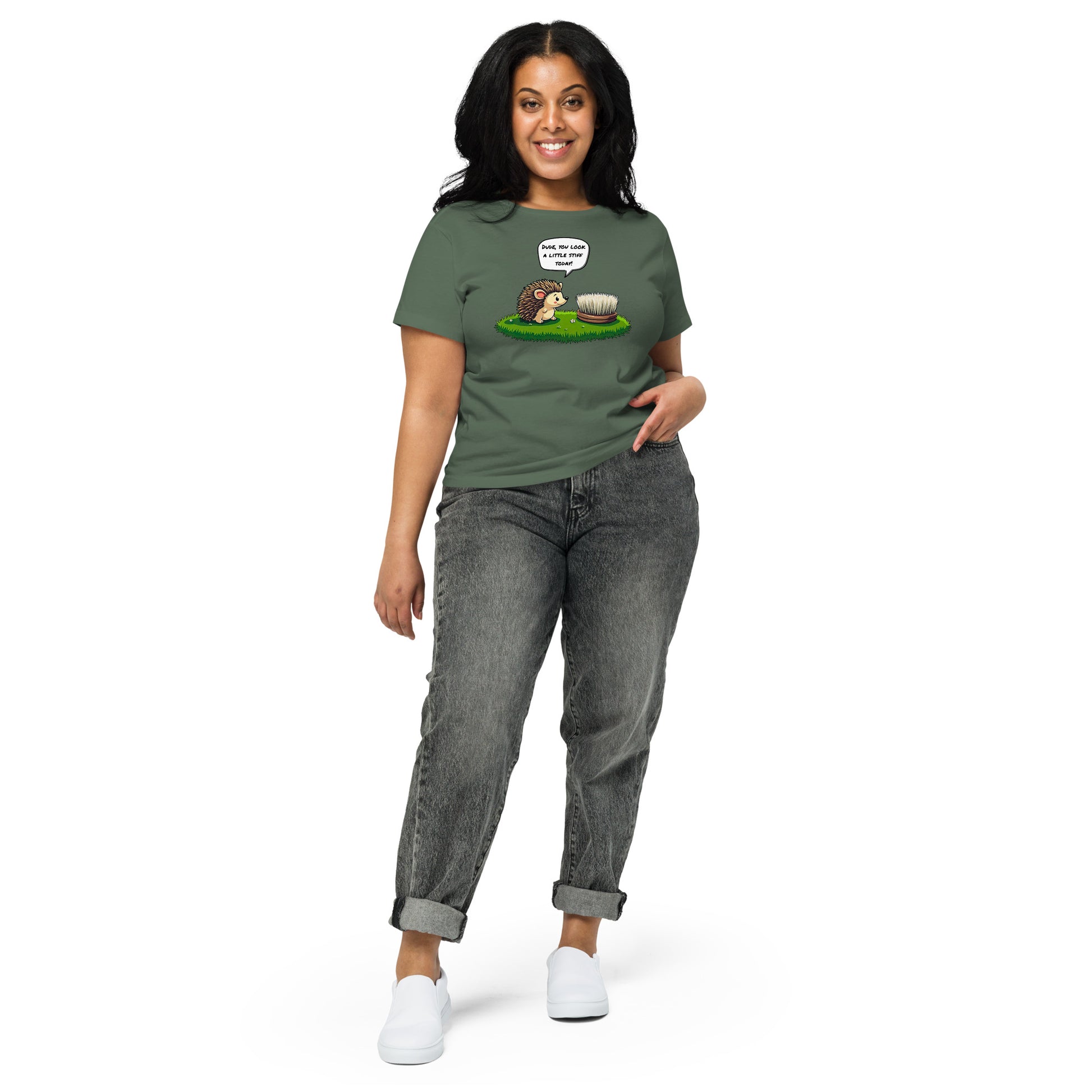 Product mockup. Full-body view of a woman standing and wearing a pine green high-waisted t-shirt with the hedgehog and scrubbing brush cartoon graphic on the front. She is also wearing relaxed-fit gray jeans and white shoes. The setting is a plain white background.