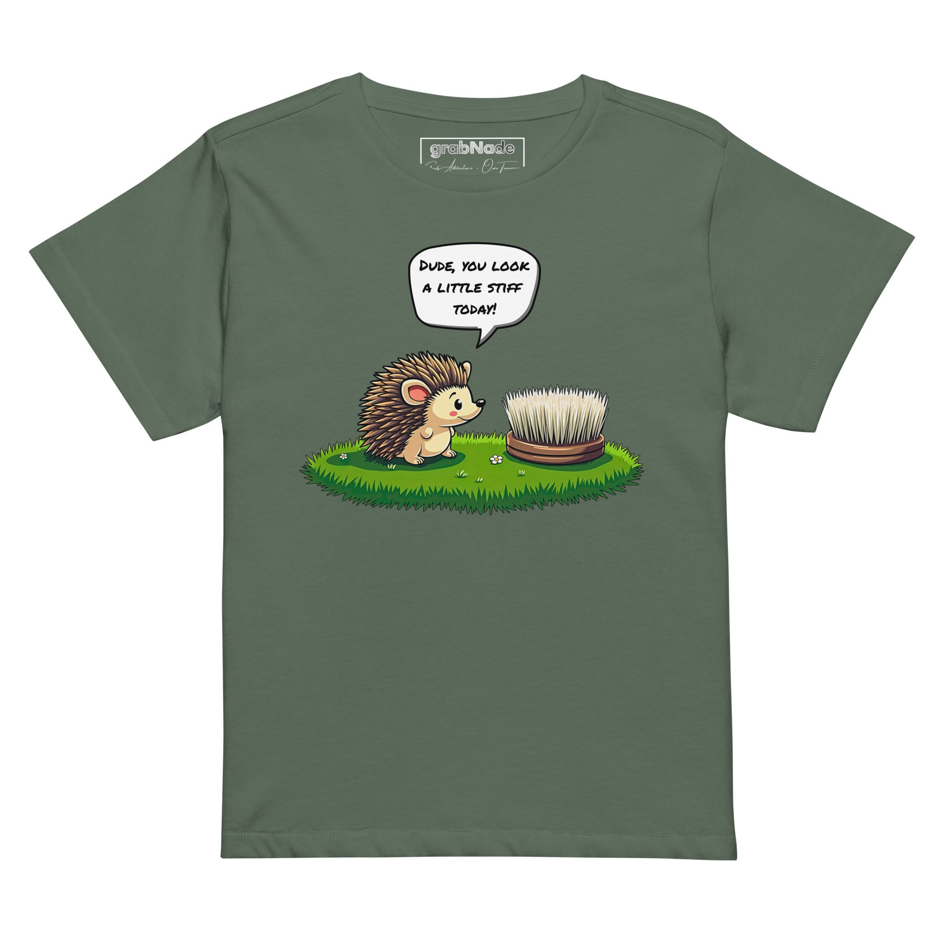 Product mockup. Green pine high-waisted women's t-shirt laid flat against a plain background. A colorful cartoon graphic of a hedgehog with a speech bubble—'Dude, you look a little stiff today!'—faces a scrubbing brush on grass. The shirt label at the collar reads 'grabNade.