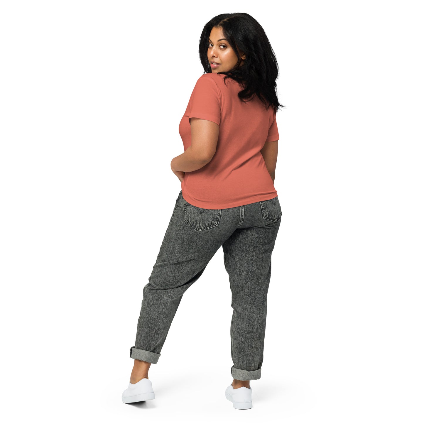 Product mockup. Back view of a woman wearing a red sorbet high-waisted t-shirt and light-colored pants. The back of the shirt is plain with no graphics or text, and she is turning her head to look at the camera, set against a clean white backdrop.