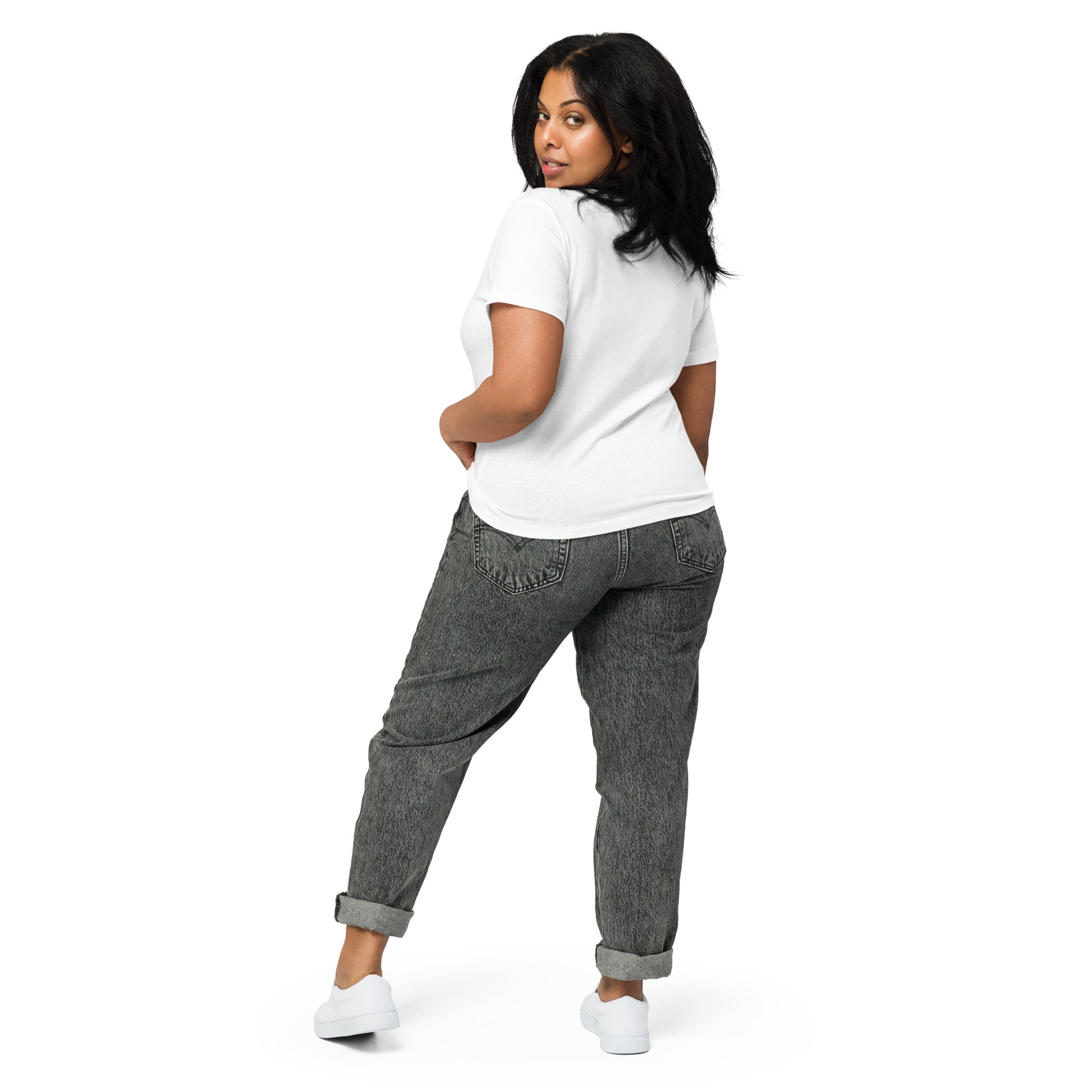 Product mockup. Back view of a woman wearing a white high-waisted t-shirt and light-colored pants. The back of the shirt is plain with no graphics or text, and she is turning her head to look at the camera, set against a clean white backdrop.
