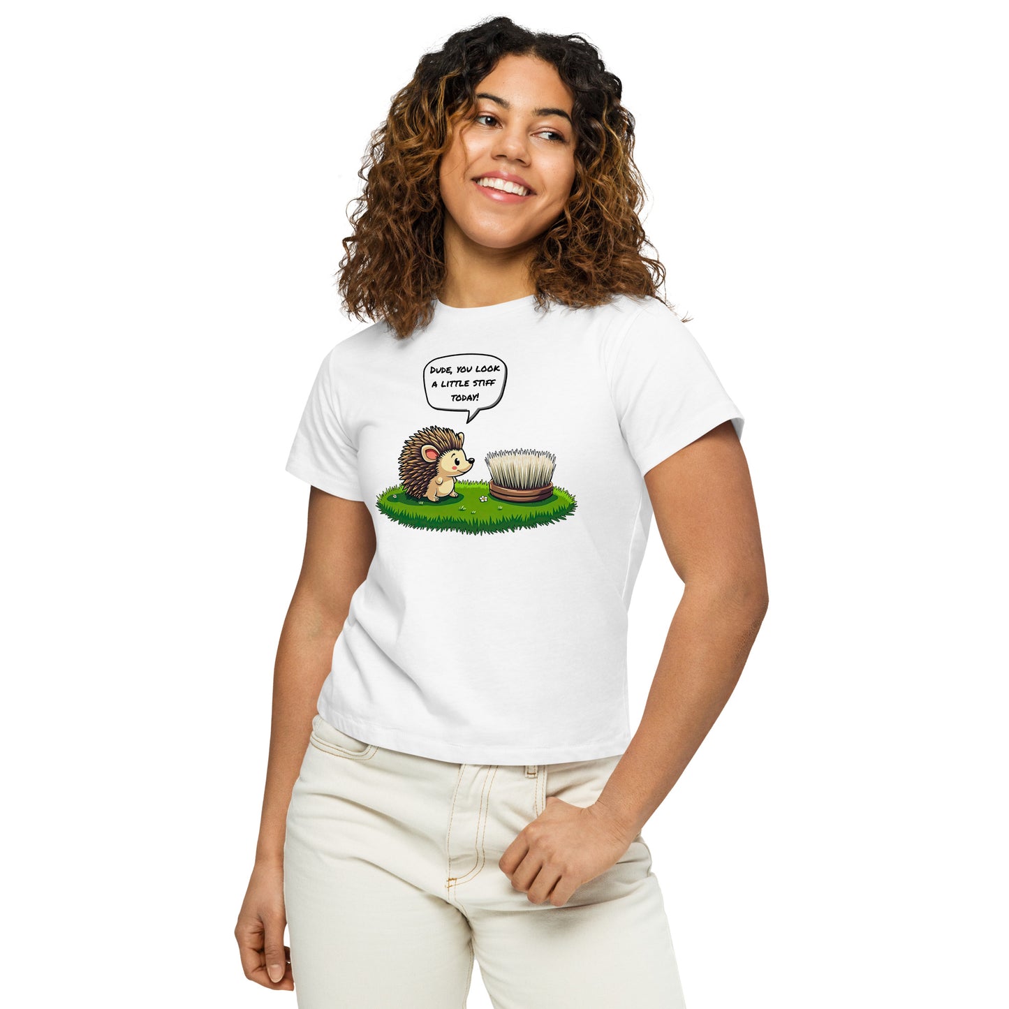 Product mockup. Close-up, front view of a woman in a white high-waisted t-shirt with a playful hedgehog and scrubbing brush design. She has curly hair, is smiling, and wears light-colored jeans, posing against a white background.