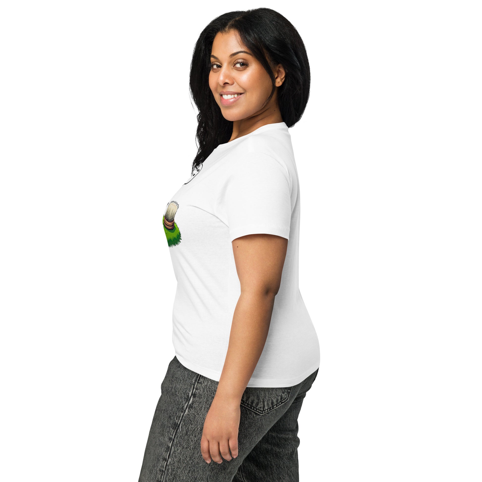 Product mockup. Side view of a woman wearing a white high-waisted t-shirt with a colorful cartoon graphic featuring a hedgehog and a scrubbing brush, and fitted gray jeans. She is smiling and standing against a simple white background.