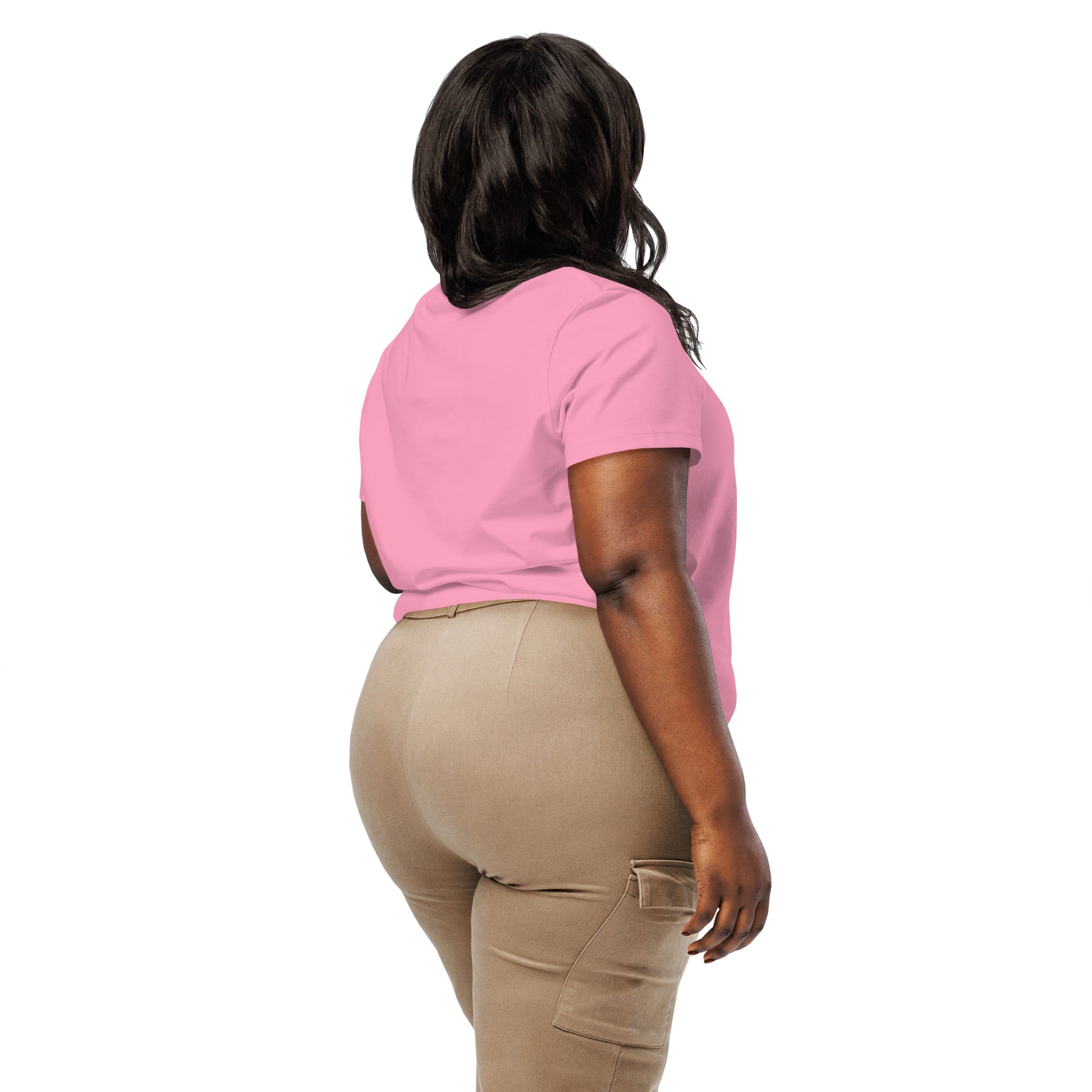 Product mockup. A woman shown from behind wearing a plain pink organic cotton t-shirt with short sleeves. The shirt has a relaxed fit, and no design or graphics appear on the back. She is also wearing khaki pants with side pockets.