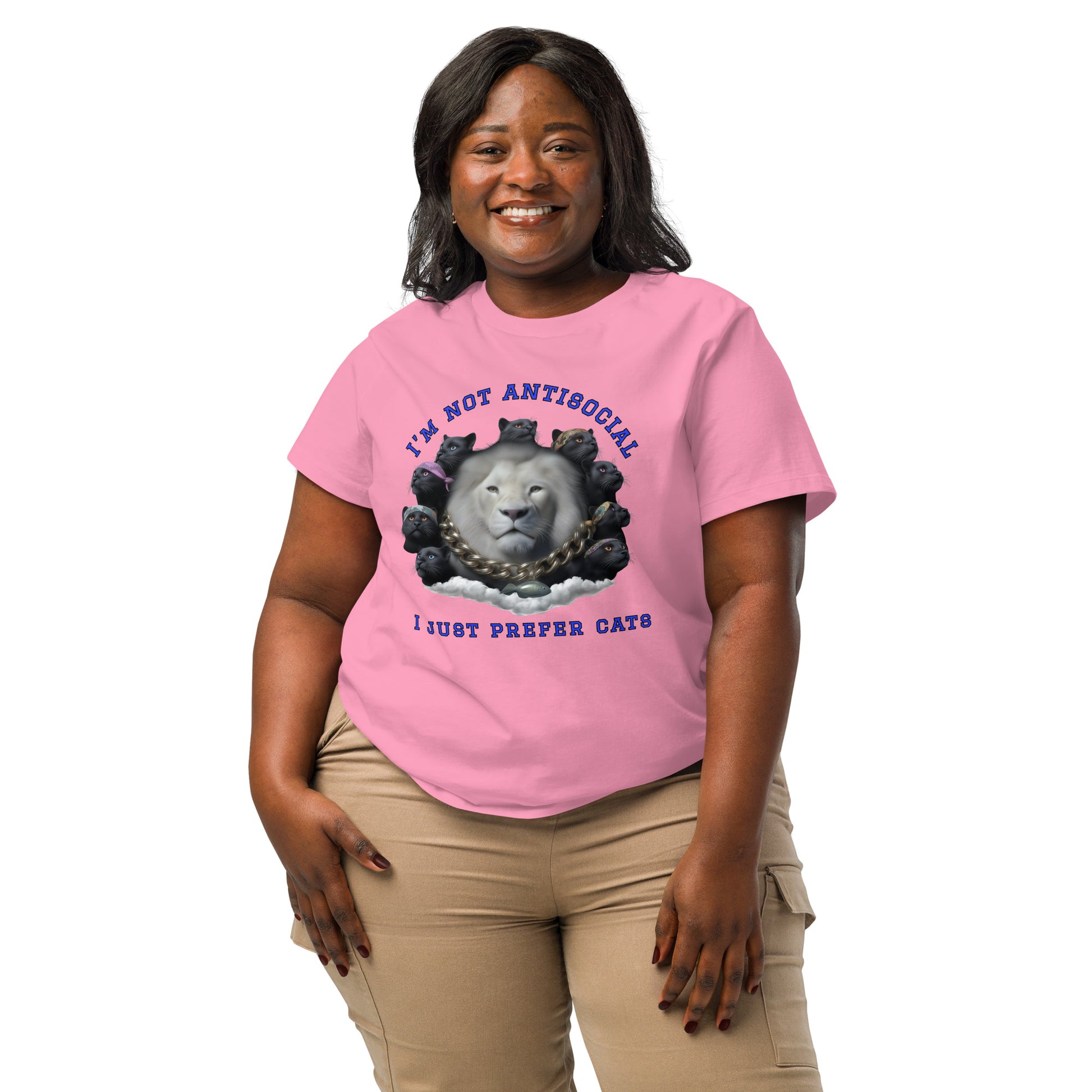 Product mockup. A woman wearing a 2XL pink organic cotton t-shirt featuring a bold graphic on the front: a large white lion's head surrounded by black panthers wearing colorful bandanas, arranged in a circle. Above the graphic is the phrase 'I'M NOT ANTISOCIAL' and below it reads 'I JUST PREFER CATS' in blue capital letters.