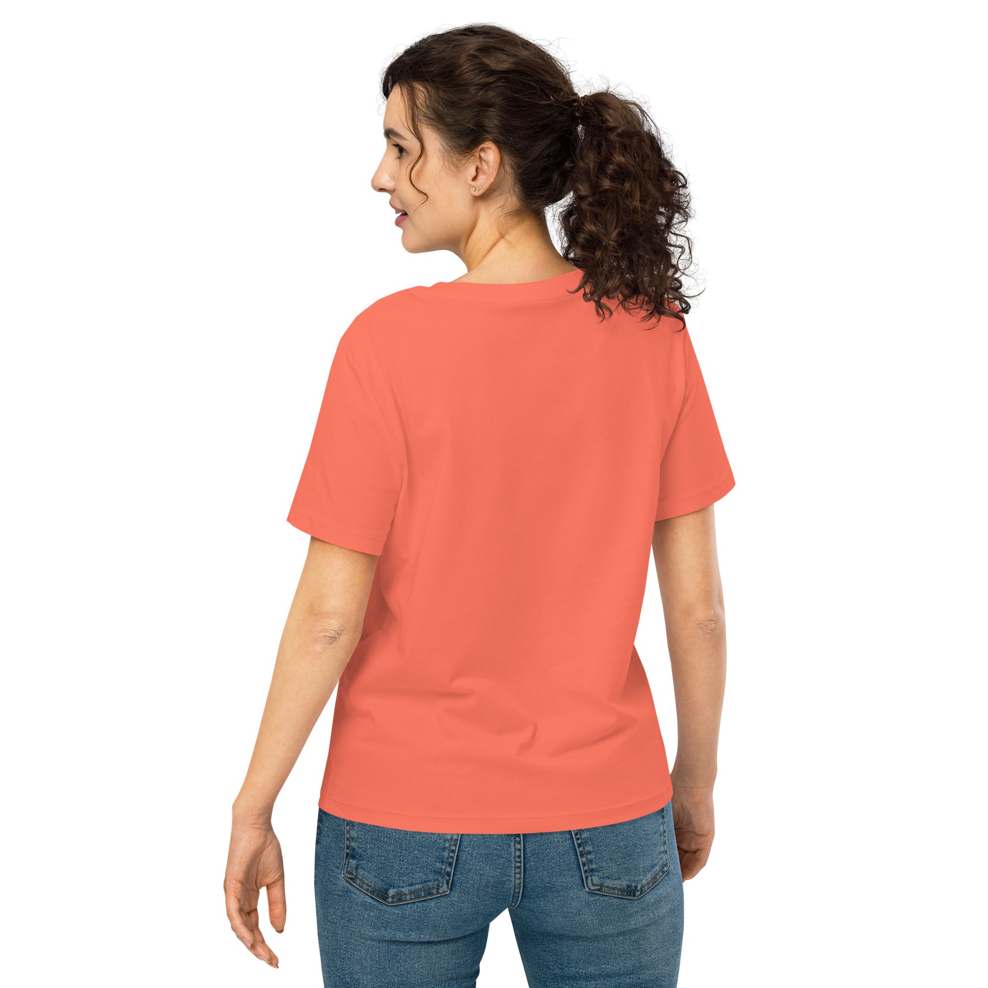 Product mockup. A woman shown from behind wearing a plain orange organic cotton t-shirt with short sleeves. The shirt has a relaxed fit, and no design or graphics appear on the back. She is also wearing blue jeans pants.