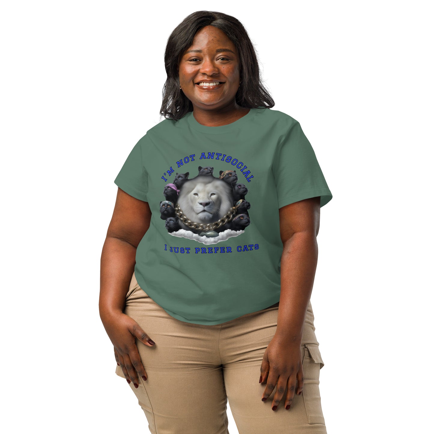 Product mockup. A woman wearing a 2XL green organic cotton t-shirt featuring a bold graphic on the front: a large white lion's head surrounded by black panthers wearing colorful bandanas, arranged in a circle. Above the graphic is the phrase 'I'M NOT ANTISOCIAL' and below it reads 'I JUST PREFER CATS' in blue capital letters.