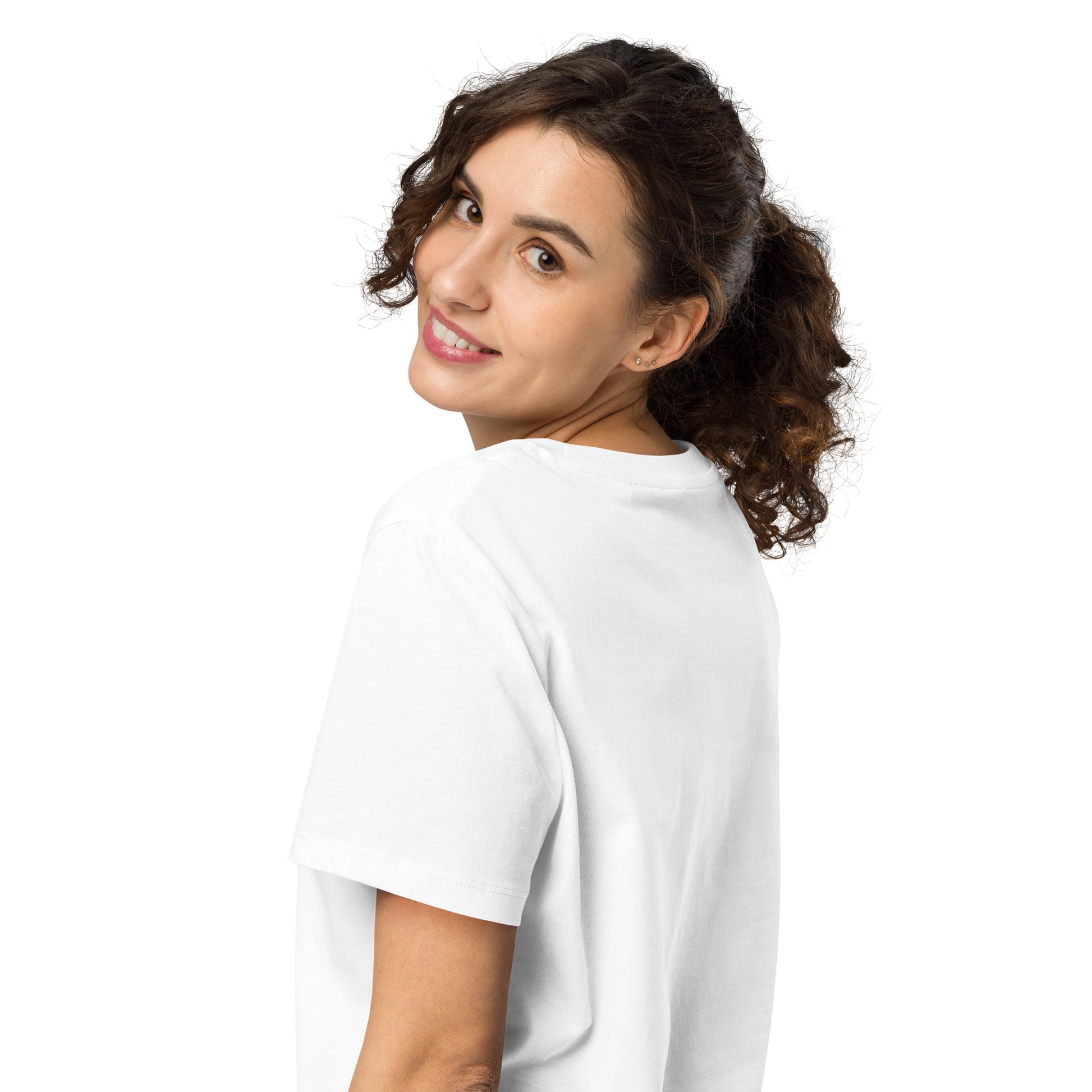 Product mockup. A woman with curly brown hair in a ponytail, shown from behind and looking over her shoulder with a smile, wearing a plain white organic cotton t-shirt. The shirt has a soft, regular fit and no visible design on the back.