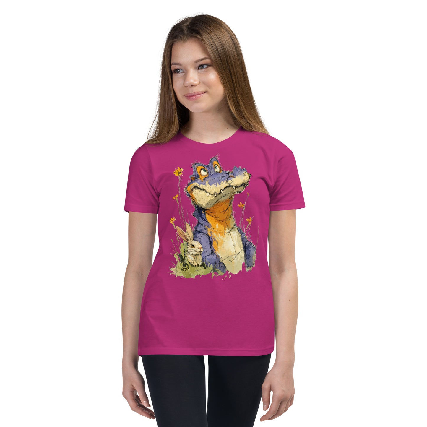 Product mockup. Ultra-soft premium youth pink t-shirt featuring whimsical colorful illustration of a playful purple and orange alligator sitting in grass next to a small rabbit and yellow wildflowers, modeled on young girl.