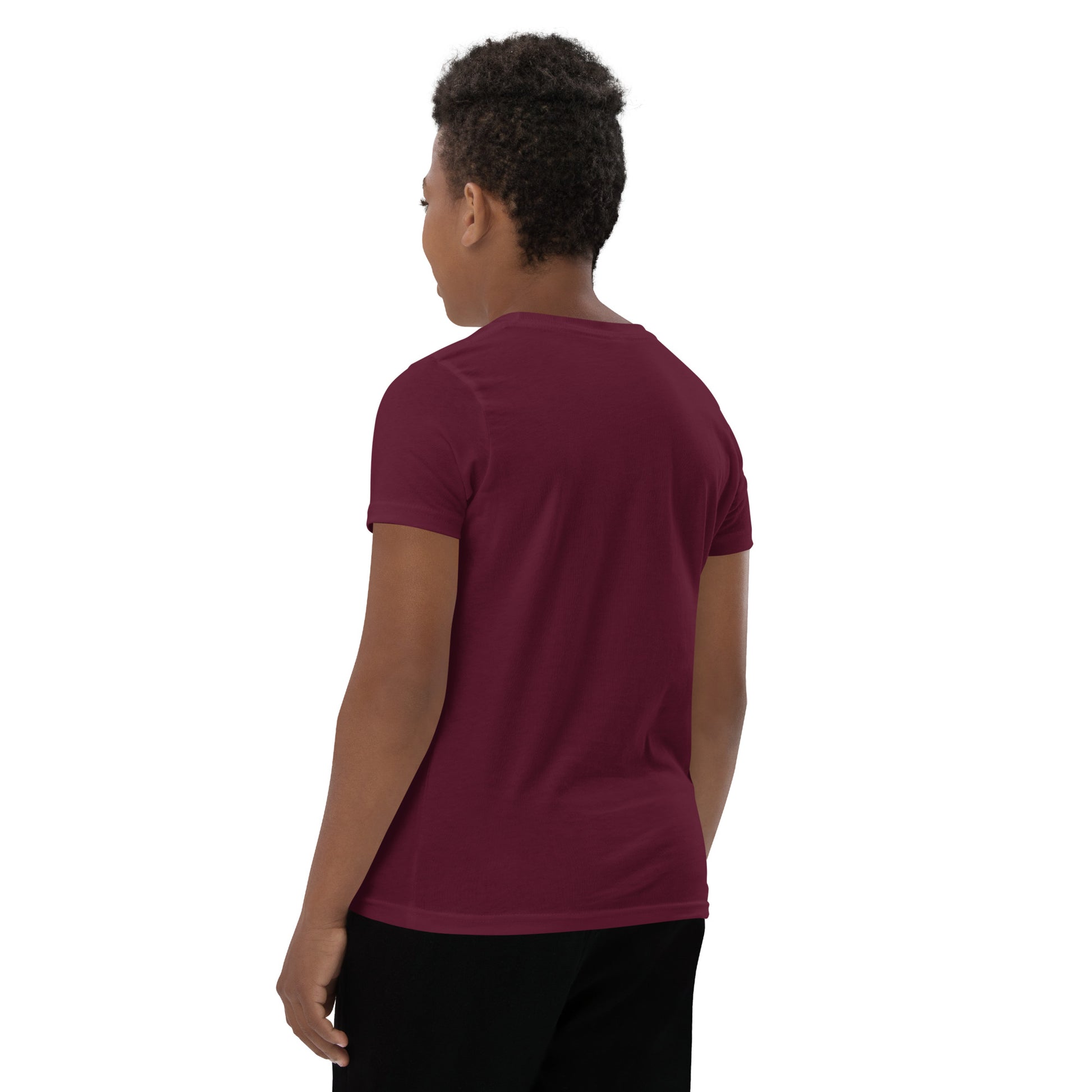 Product mockup. A boy shown from behind wearing a plain maroon, short-sleeve t-shirt and black pants. His curly hair is closely cropped, and the back of the shirt is blank with no visible design or graphics.