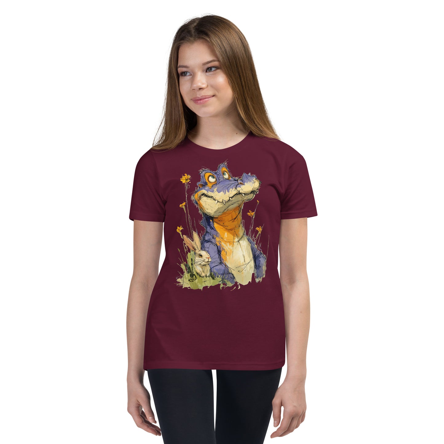Product mockup. Ultra-soft premium youth maroon t-shirt featuring whimsical colorful illustration of a playful purple and orange alligator sitting in grass next to a small rabbit and yellow wildflowers, modeled on young girl.