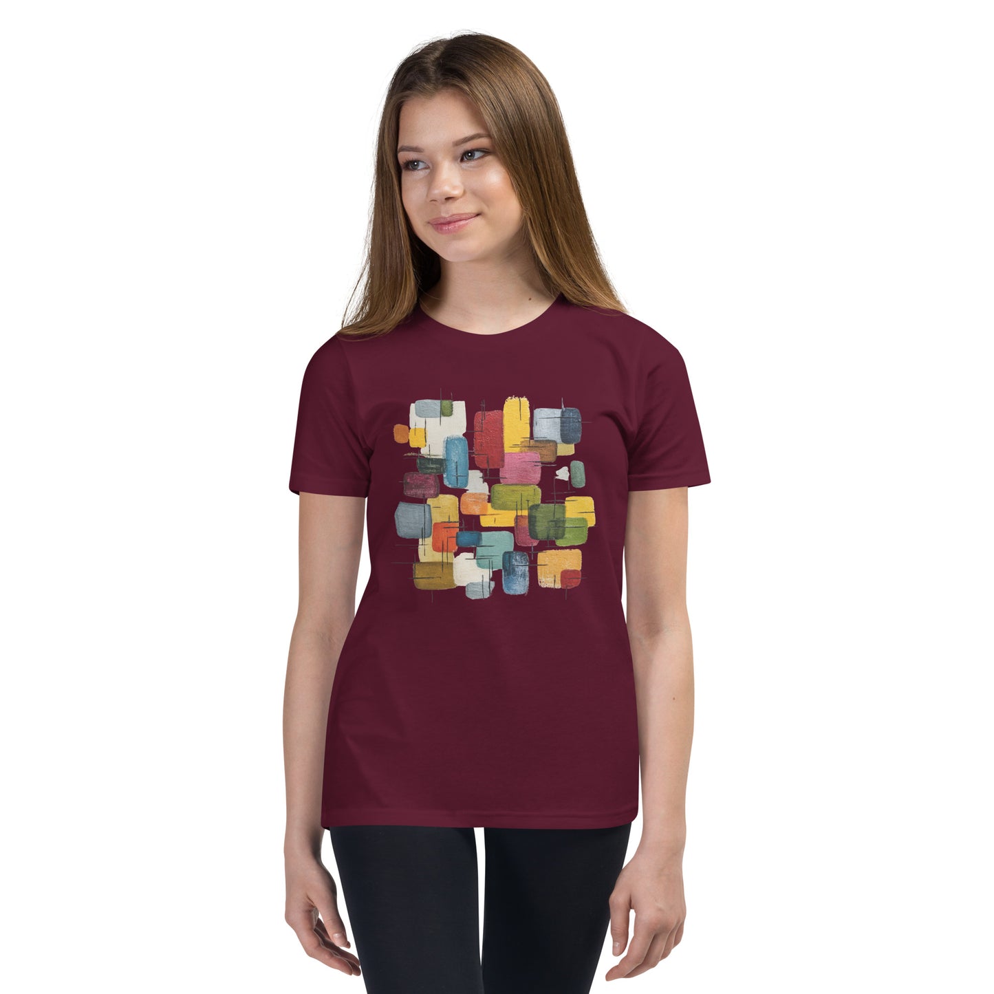 Product mockup. A young woman wearing a maroon, short-sleeve t-shirt with a large, colorful abstract design on the front. The design features overlapping rounded rectangles in red, yellow, teal, blue, green, and orange, with fine black sketch lines, creating a playful and modern look. She is also wearing black leggings.