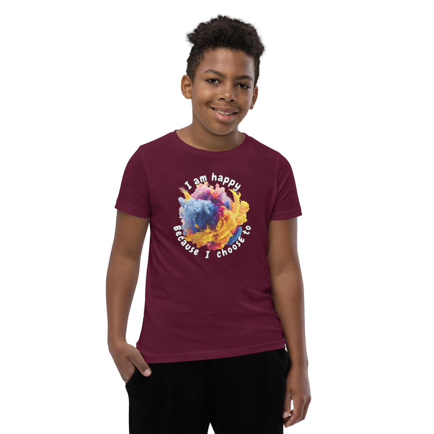 Product mockup. A smiling young boy wearing a maroon t-shirt with a colorful, cloud-like burst of blue, pink, purple, and yellow at the chest. Above and below the design, curved white text reads, 'I am happy Because I choose to,' in a playful, rounded font.