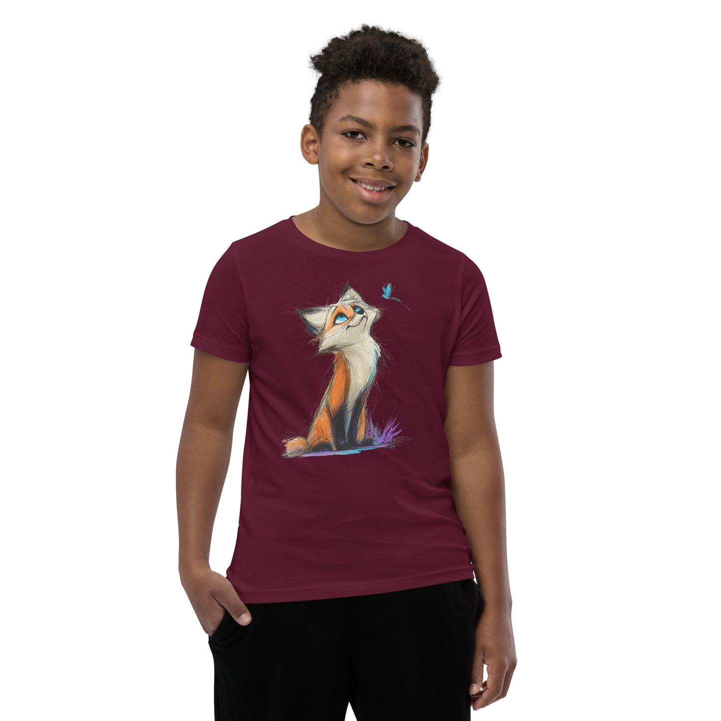 Product mockup. A smiling young boy wearing a maroon t-shirt adorned with a playful, sketch-style illustration of a bright orange and white fox sitting on the ground, gazing up curiously at a small blue butterfly fluttering near its face. The background is clean and studio-lit, emphasizing the colorful and whimsical design of the shirt.
