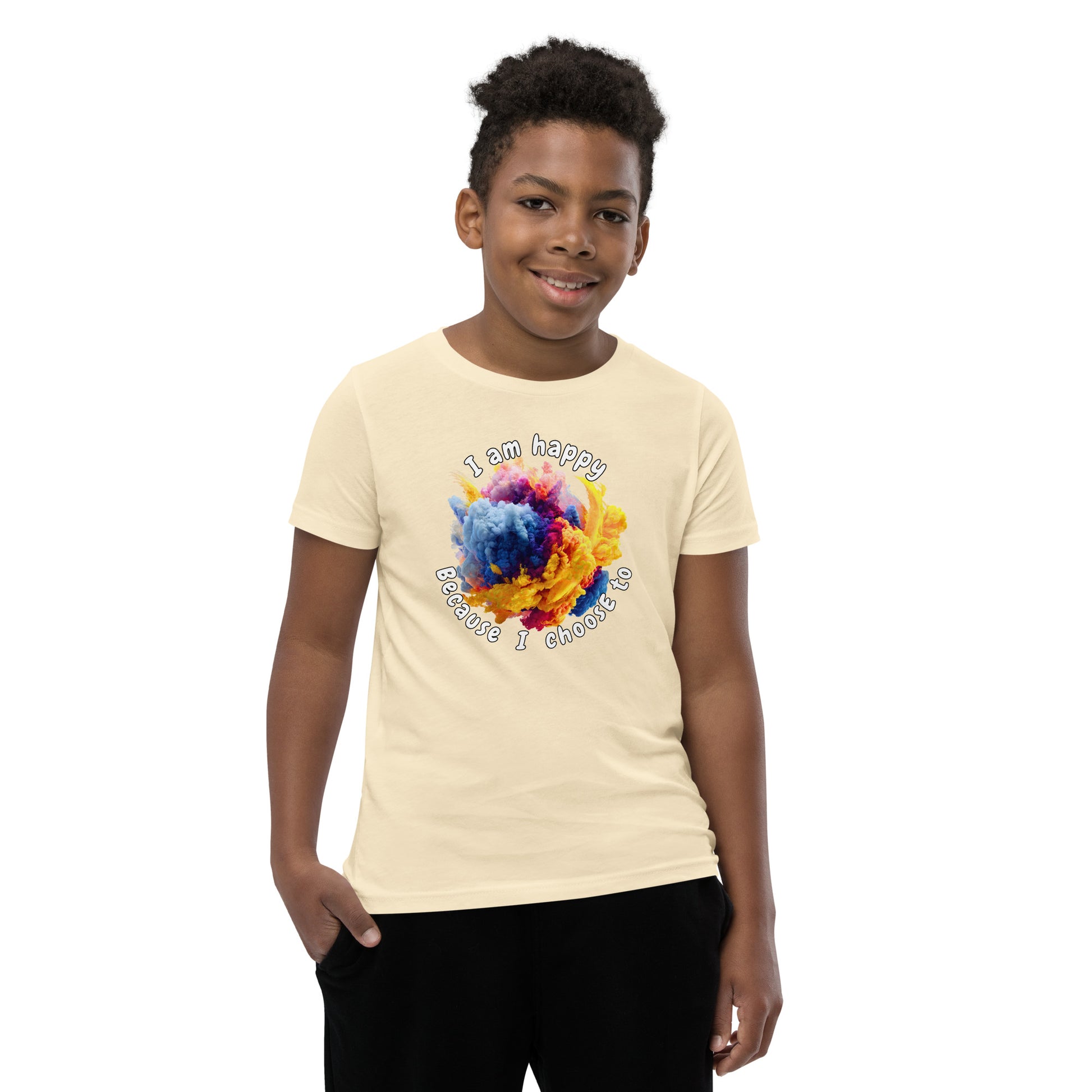 Product mockup. A smiling young boy wearing a beige t-shirt with a colorful, cloud-like burst of blue, pink, purple, and yellow at the chest. Above and below the design, curved white text reads, 'I am happy Because I choose to,' in a playful, rounded font.
