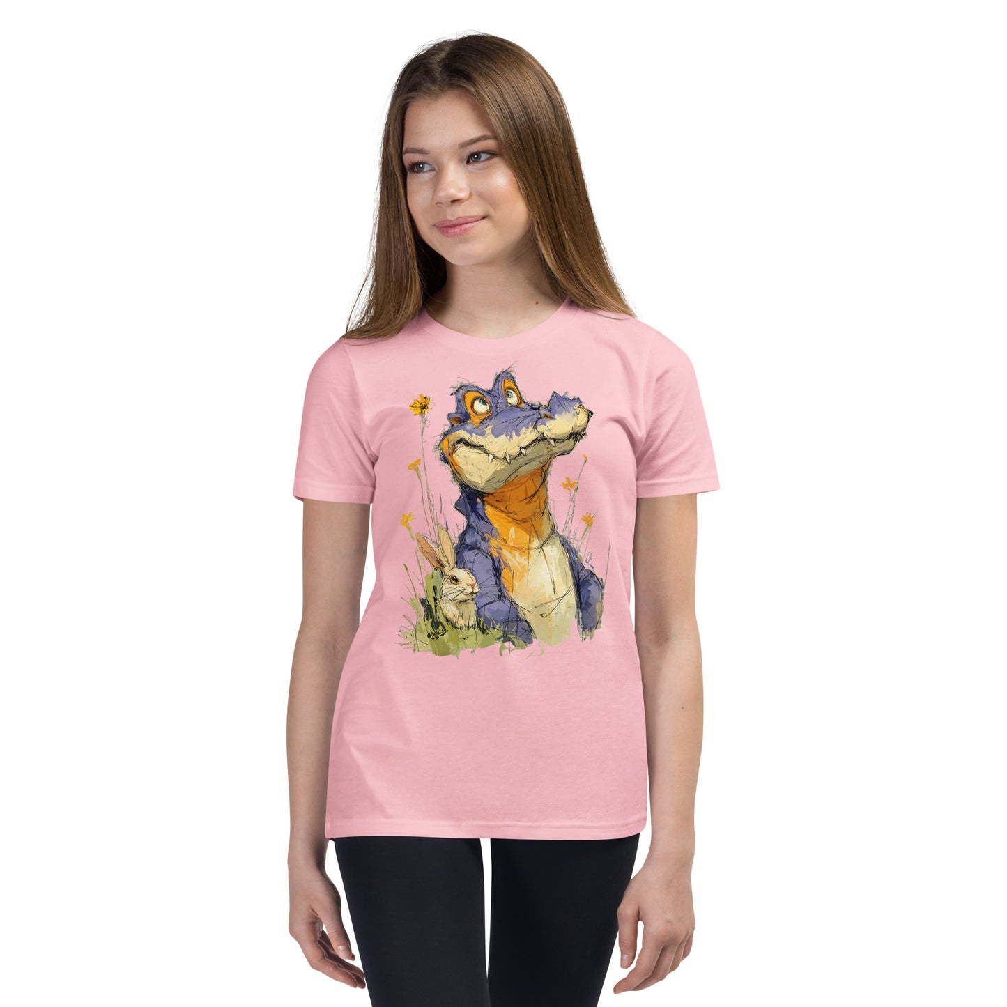 Product mockup. Ultra-soft premium youth pink t-shirt featuring whimsical colorful illustration of a playful purple and orange alligator sitting in grass next to a small rabbit and yellow wildflowers, modeled on young girl.